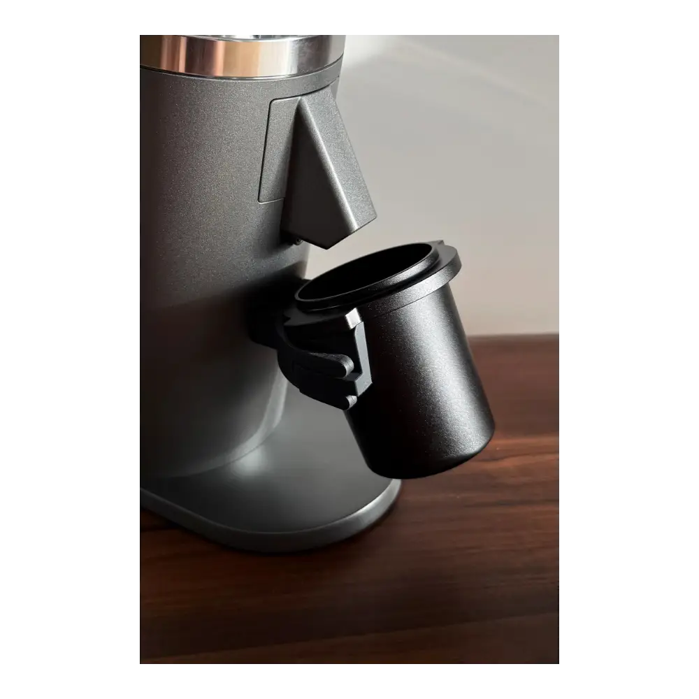 Black DF64 coffee grinder with a black aluminium dosing cup on a wooden surface