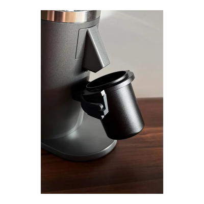 Black DF64 coffee grinder with a black aluminium dosing cup on a wooden surface